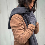 Dunkelhaarige Frau mit mittelbraunem Mantel kuschelt sich in ihre passende Kombi aus anthrazit farbenem Kuschel Schal und passenden Handschuhen aus reiner Bio Baumwolle. Fair und nachhaltig handgefertigt in Deutschland vom Microlabel Liebe-Deinen-Planeten