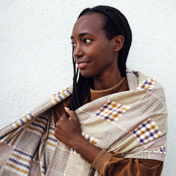 Frau mit langen Rastas hat sich einen karierten XL Schal um die Schultern gelegt. Der Schal aus nachhaltigem Deadstock Material ist nur einer vo vielen nachhaltigen und fairen Schals, Tüchern und Loops vom Microlabel "Liebe Deinen Planeten"